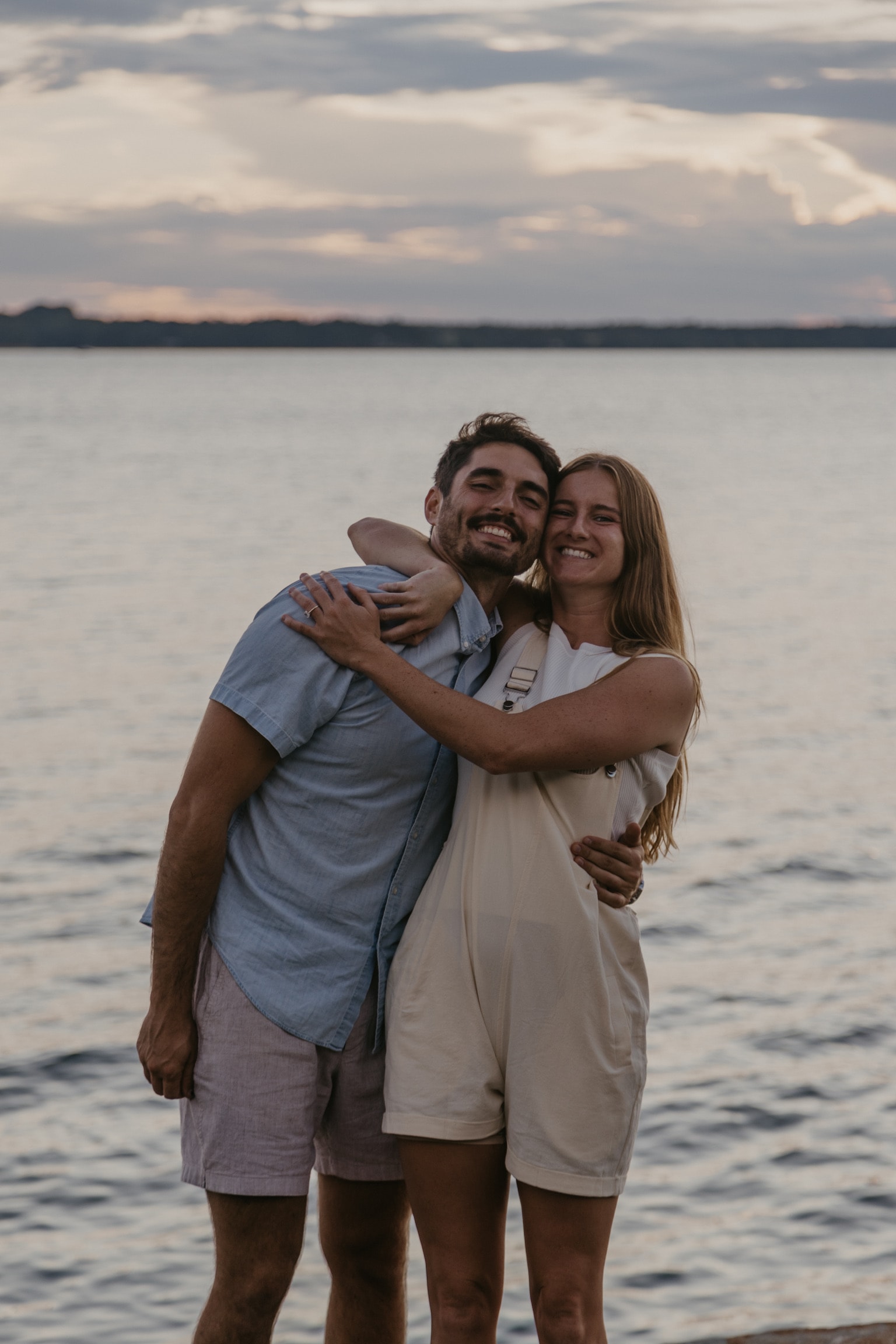 Luke and Bailey standing together by the water at dusk