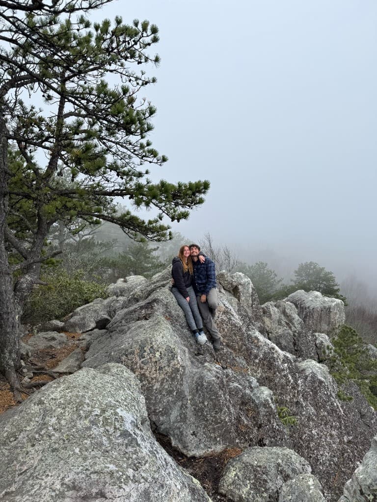 Luke and Bailey sitting together on a mountain rock